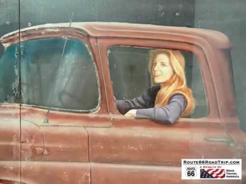 It's a girl, my Lord, in a flatbed Ford slowin' down to take a look at me ... at the Standing on the Corner Park in WInslow Arizona